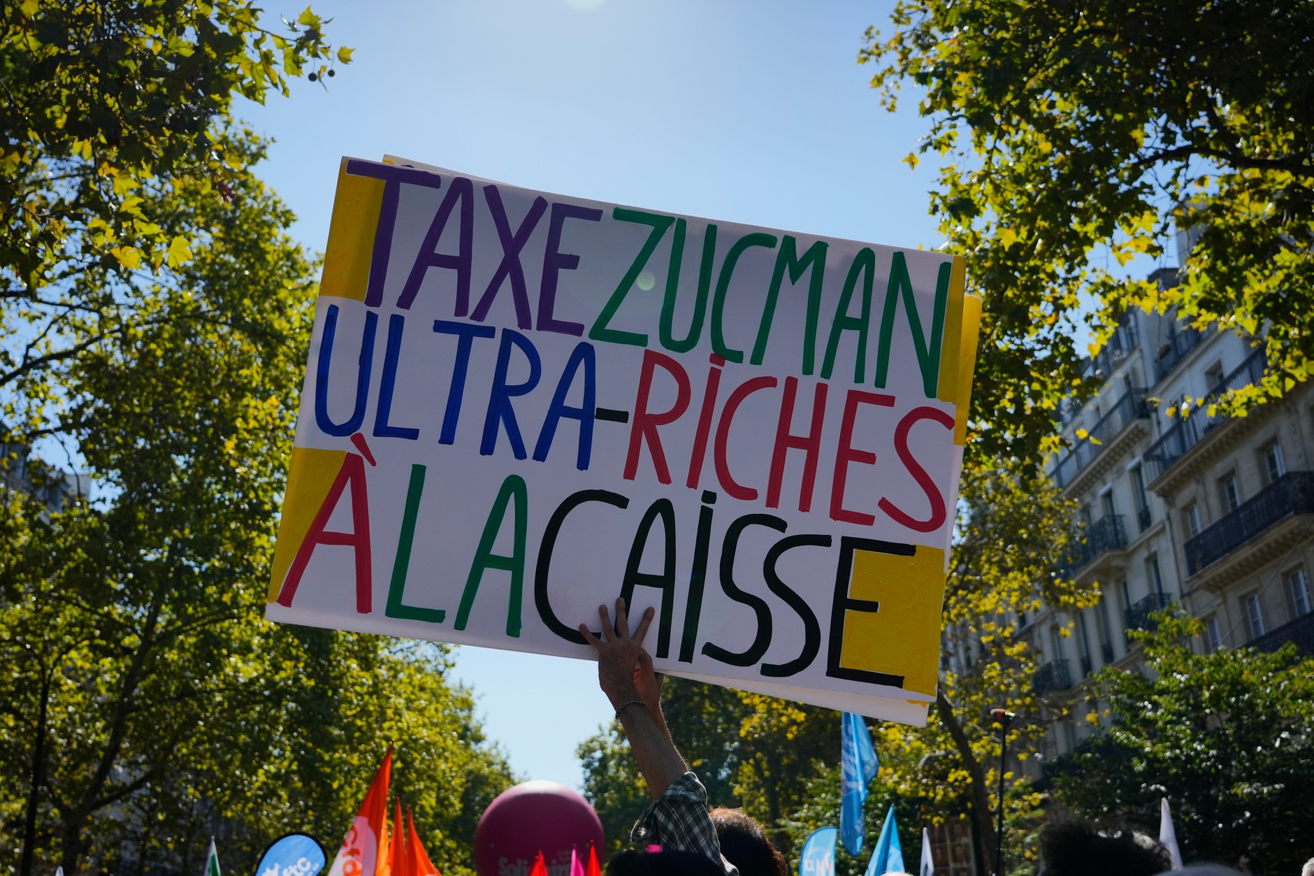 Demonstranci trzymają transparent popierający tzw. podatek Zucmana podczas wiecu przeciwko środkom oszczędnościowym, Paryż, 18 września 2025 r.